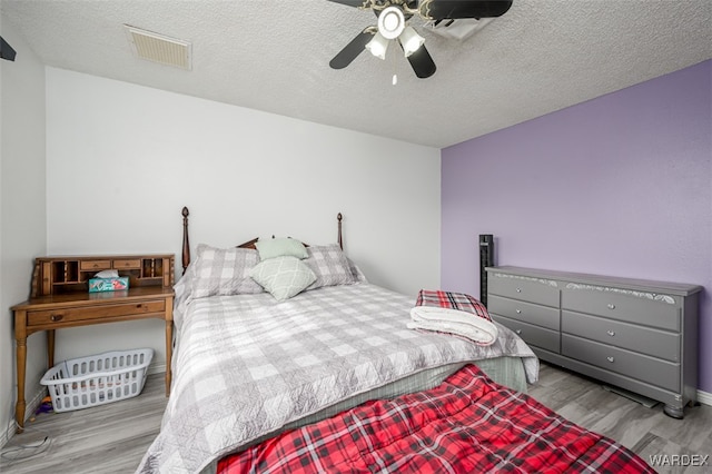 bedroom with visible vents, ceiling fan, a textured ceiling, and light wood finished floors