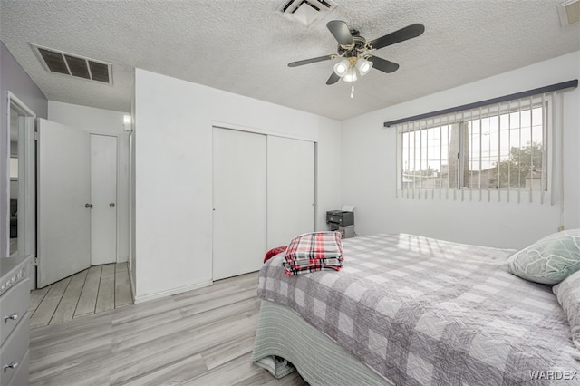 bedroom featuring light wood-style flooring, a closet, and visible vents