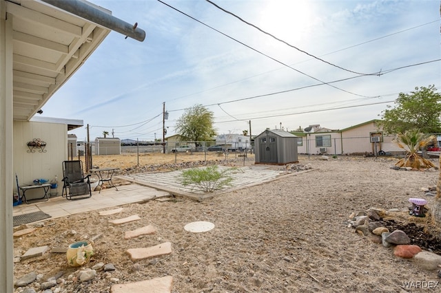 view of yard featuring a storage shed, a patio area, an outdoor structure, and fence