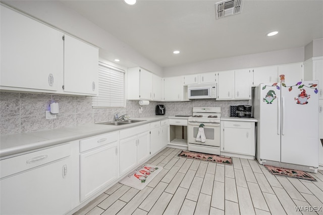 kitchen with light countertops, white appliances, white cabinetry, and a sink