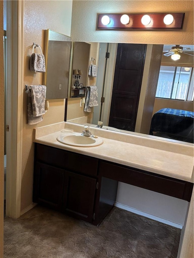 bathroom with a ceiling fan, vanity, and a textured wall