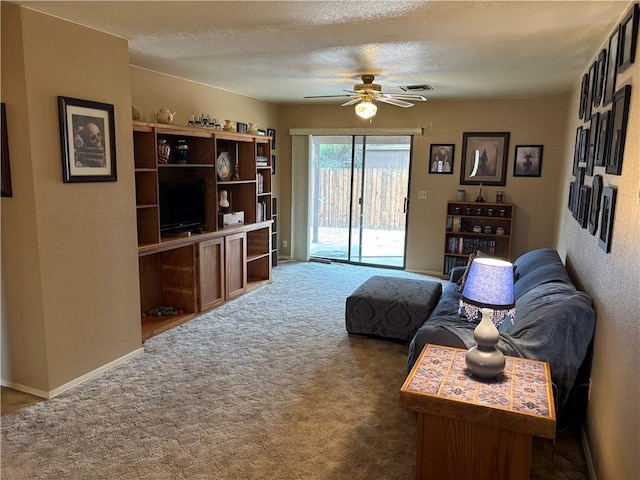 living area with a textured ceiling, carpet, a ceiling fan, and visible vents