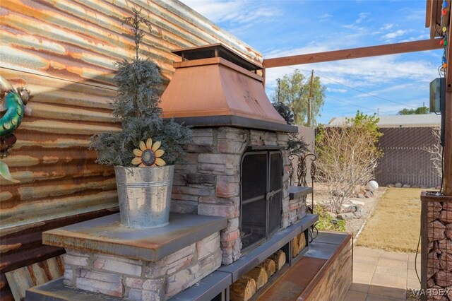 exterior details featuring stone siding, an outdoor stone fireplace, and fence