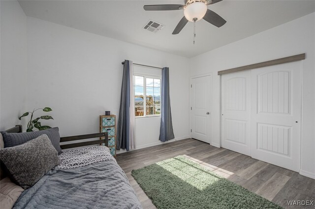 bedroom featuring baseboards, visible vents, a ceiling fan, wood finished floors, and a closet