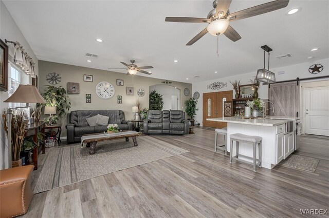 living room featuring light wood finished floors, a barn door, and visible vents