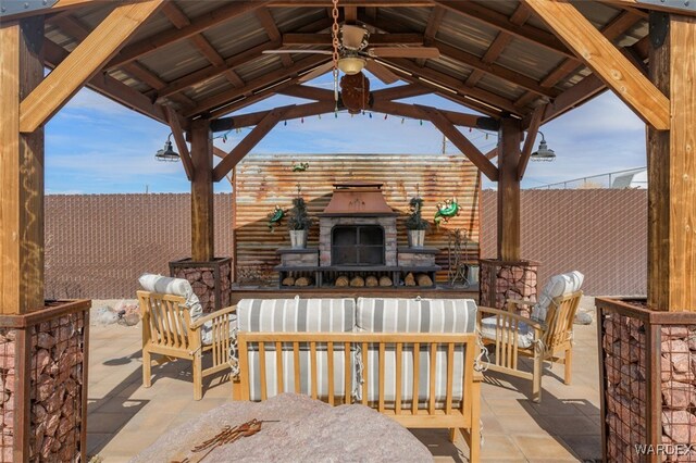 view of patio / terrace with fence, an outdoor stone fireplace, and a gazebo