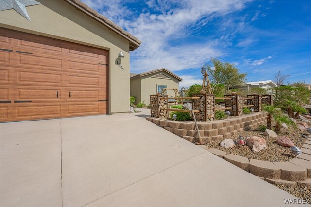 view of property exterior with concrete driveway, a tile roof, and stucco siding