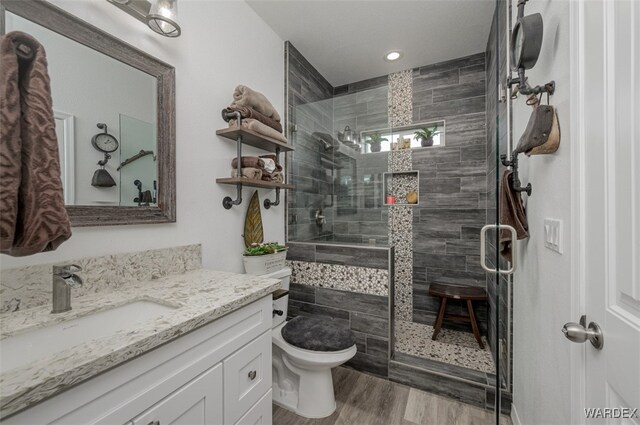 full bathroom featuring toilet, a shower stall, vanity, and wood finished floors