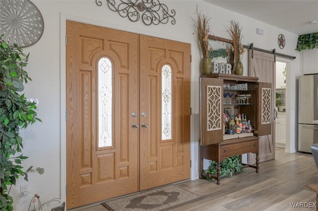 foyer entrance with a barn door and wood finished floors