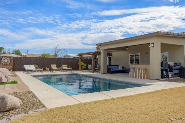 view of swimming pool with ceiling fan, fence, outdoor dry bar, a pergola, and a patio area