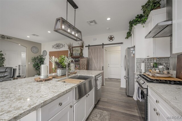 kitchen featuring stainless steel appliances, white cabinetry, and wall chimney range hood