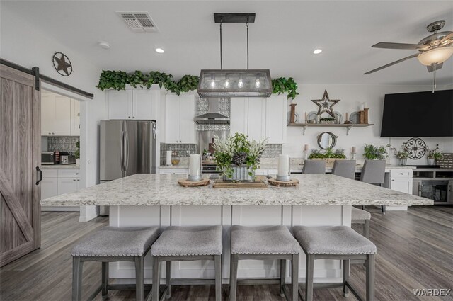 kitchen featuring visible vents, white cabinetry, a large island, and freestanding refrigerator