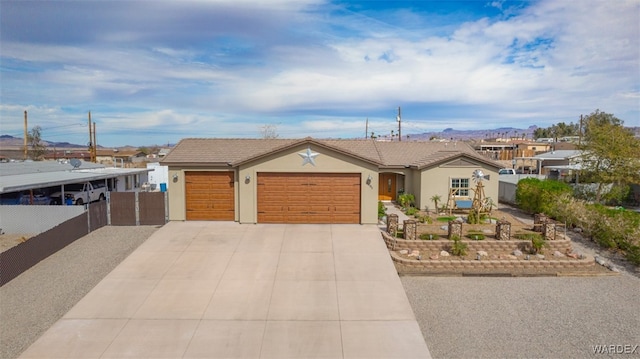 ranch-style home with concrete driveway, fence, an attached garage, and stucco siding