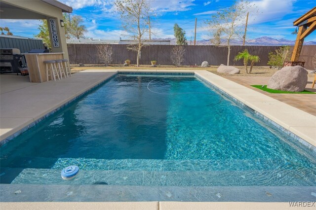 view of swimming pool with outdoor dry bar, a patio area, and a fenced backyard