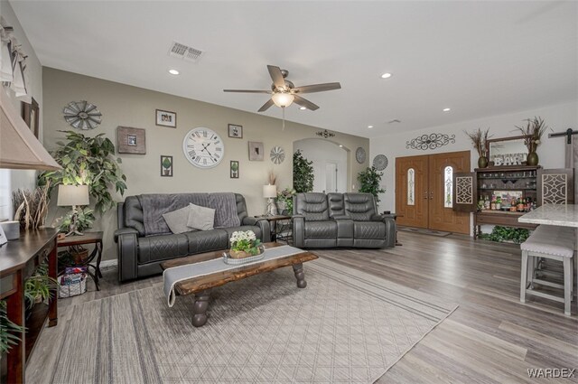 living room featuring light wood finished floors, visible vents, arched walkways, a ceiling fan, and recessed lighting