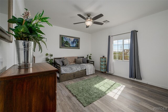 bedroom featuring ceiling fan, wood finished floors, visible vents, and baseboards