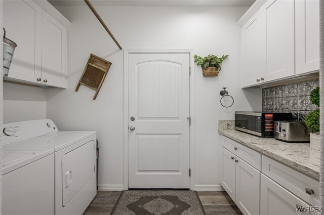 washroom with cabinet space, baseboards, dark wood-style flooring, and washing machine and clothes dryer