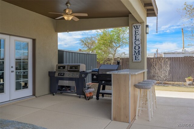 view of patio featuring french doors, outdoor dry bar, a grill, ceiling fan, and fence