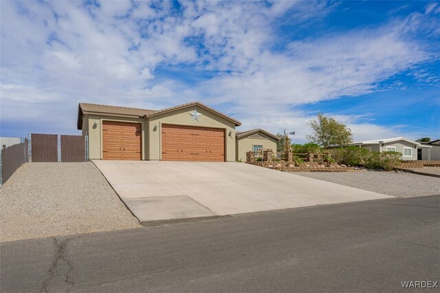 ranch-style house featuring driveway, an attached garage, fence, and stucco siding