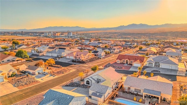 aerial view at dusk featuring a mountain view and a residential view