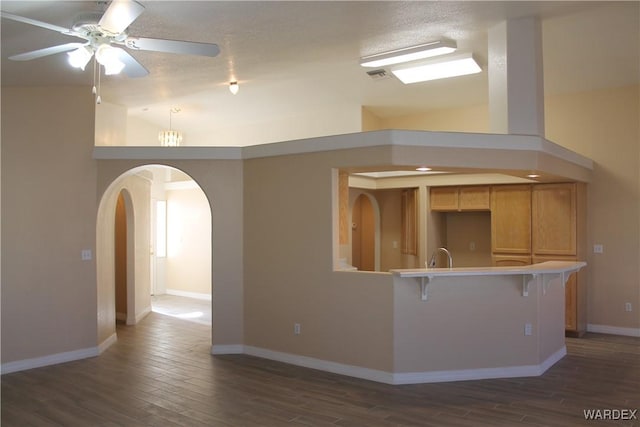 kitchen featuring lofted ceiling, dark wood-style flooring, light countertops, and arched walkways