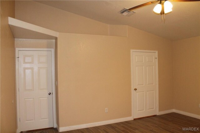 unfurnished room featuring dark wood-type flooring, visible vents, vaulted ceiling, and baseboards