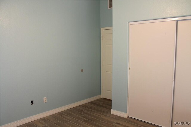 unfurnished bedroom featuring wood tiled floor, a closet, visible vents, and baseboards