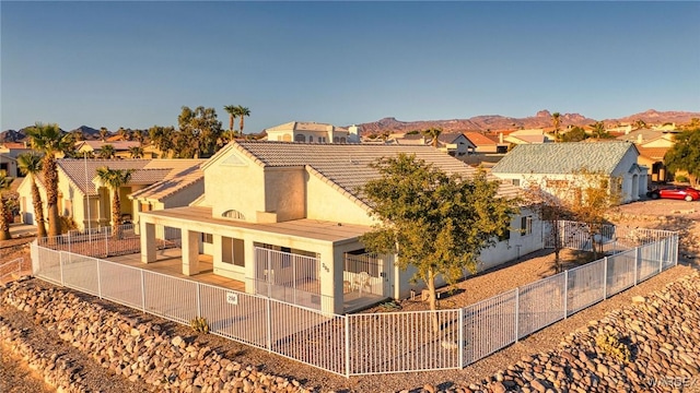 rear view of house featuring a fenced front yard, a residential view, a mountain view, and stucco siding