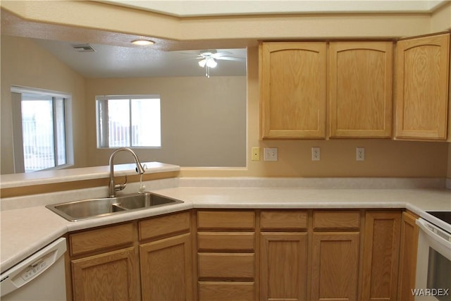 kitchen with light brown cabinets, a peninsula, white appliances, a sink, and light countertops