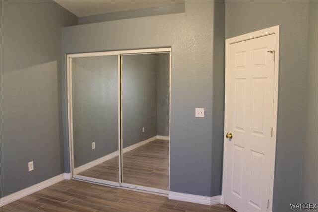 unfurnished bedroom featuring wood tiled floor, a closet, and baseboards