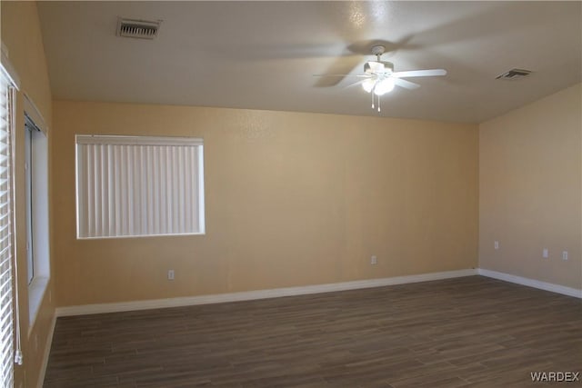 empty room with baseboards, visible vents, and dark wood finished floors