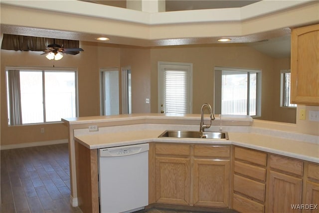 kitchen featuring light countertops, white dishwasher, a sink, and a peninsula