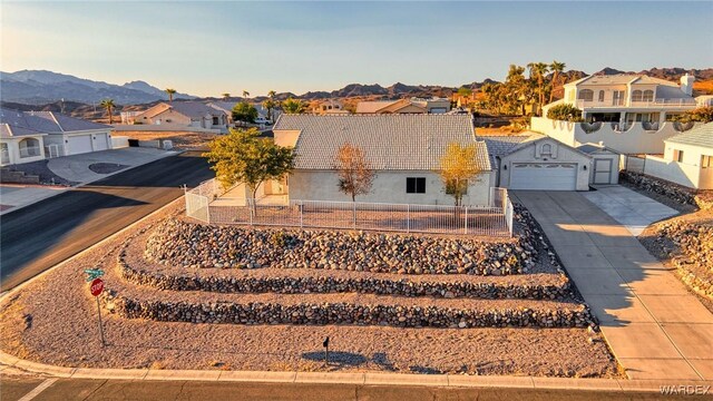 exterior space with driveway, a residential view, a tiled roof, fence, and a mountain view