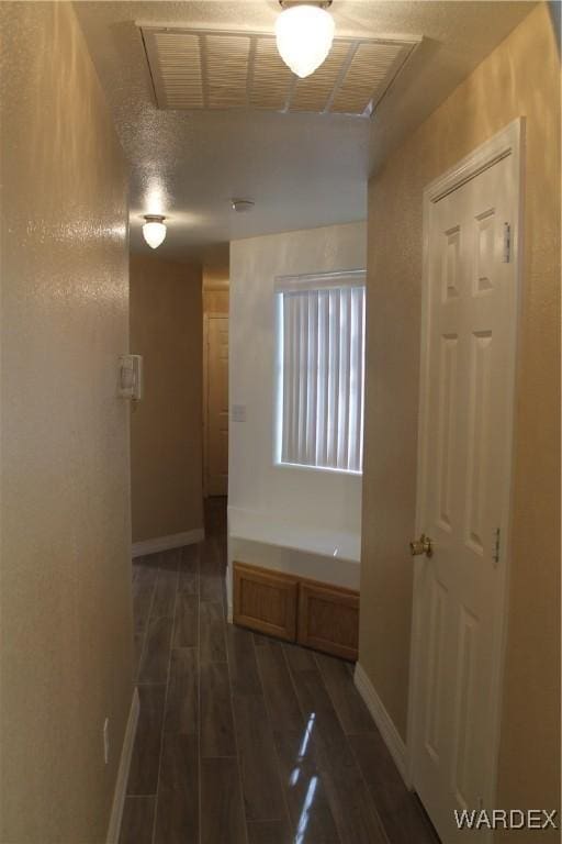 hallway with wood tiled floor, visible vents, and baseboards