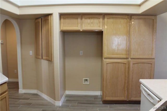 kitchen with arched walkways, dishwasher, wood tiled floor, light countertops, and light brown cabinets