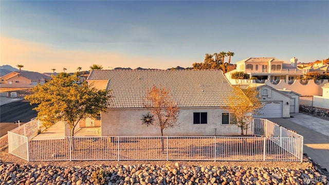 view of front of home with a tiled roof, concrete driveway, fence private yard, and stucco siding