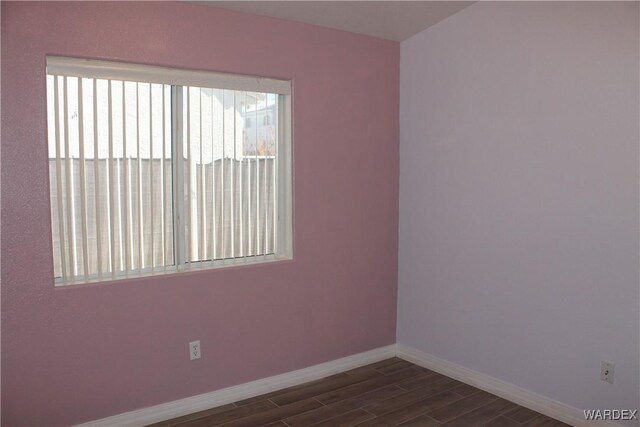 empty room with dark wood-style floors and baseboards