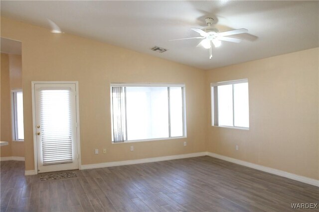 spare room featuring baseboards, visible vents, ceiling fan, dark wood-type flooring, and vaulted ceiling