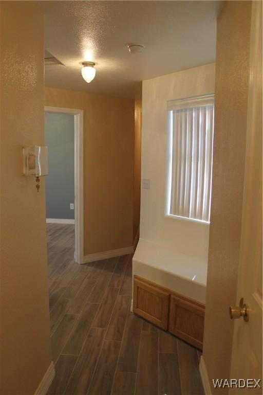 hallway with wood tiled floor, a textured ceiling, and baseboards