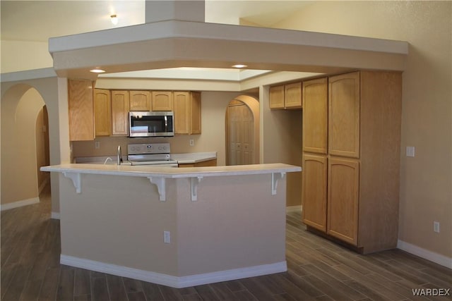 kitchen with arched walkways, stainless steel microwave, light countertops, white electric range, and light brown cabinets