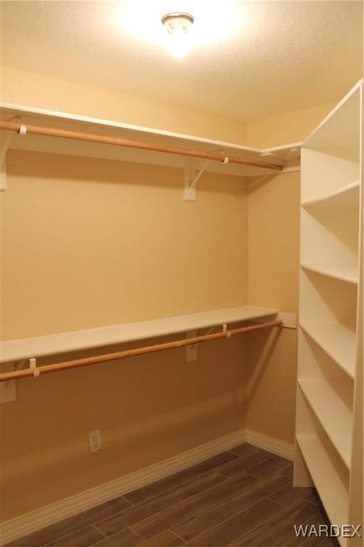 walk in closet with wood finish floors