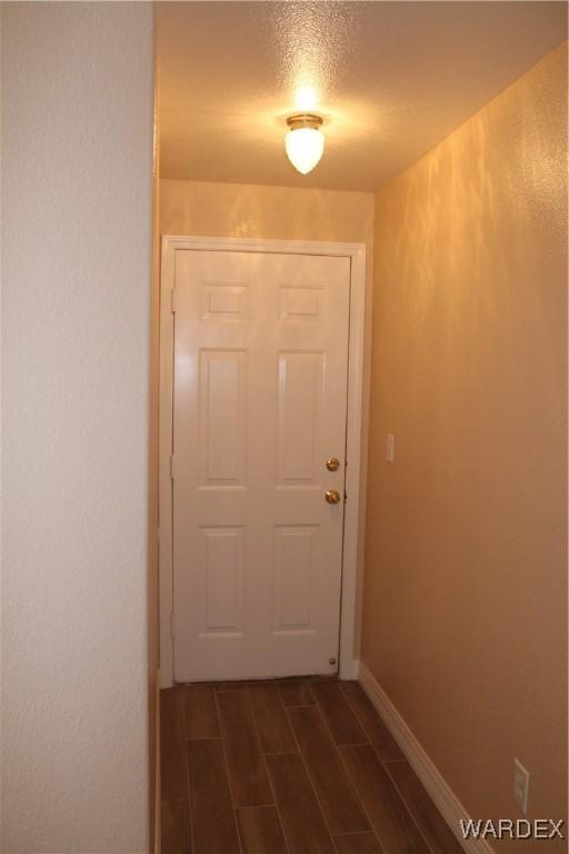 entryway with wood tiled floor, baseboards, and a textured ceiling