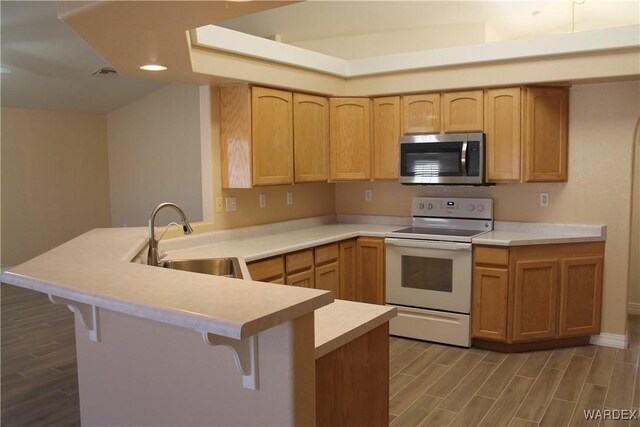 kitchen featuring electric stove, light countertops, stainless steel microwave, a sink, and a peninsula