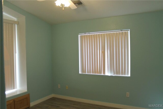 unfurnished room featuring a ceiling fan, baseboards, visible vents, and dark wood-type flooring