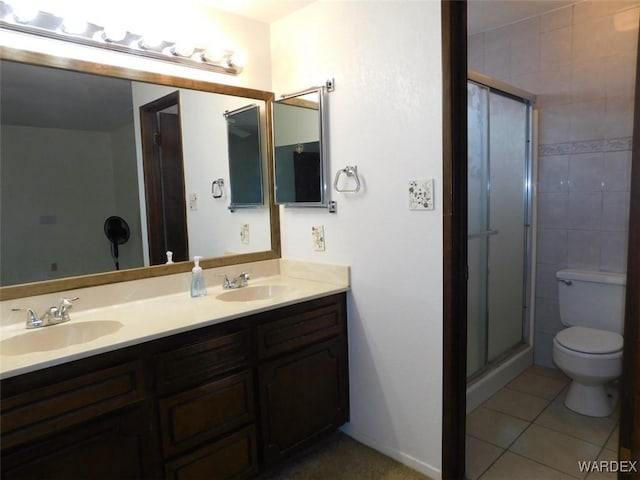 bathroom with a stall shower, a sink, toilet, and tile patterned floors