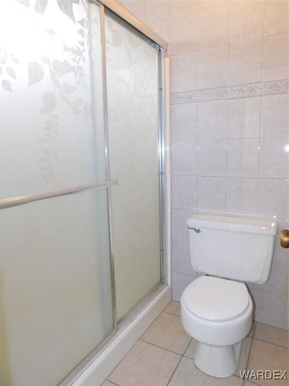 bathroom featuring a stall shower, tile walls, toilet, and tile patterned floors