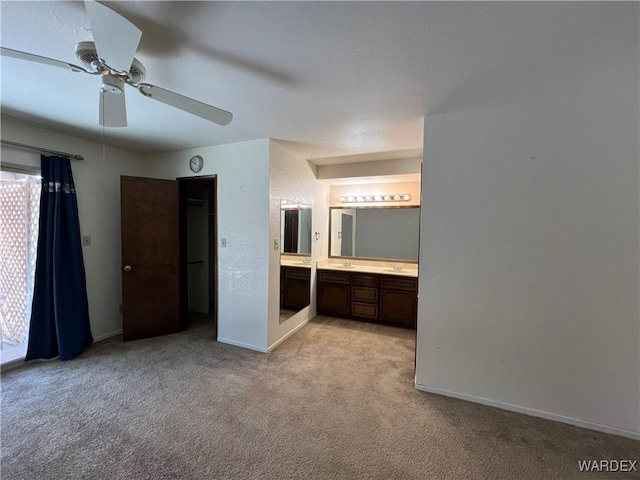 unfurnished bedroom featuring light carpet, ceiling fan, ensuite bath, and baseboards