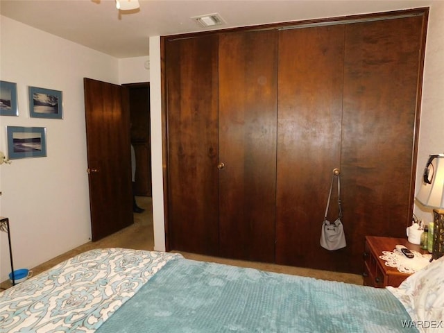 bedroom with a closet, visible vents, and carpet flooring