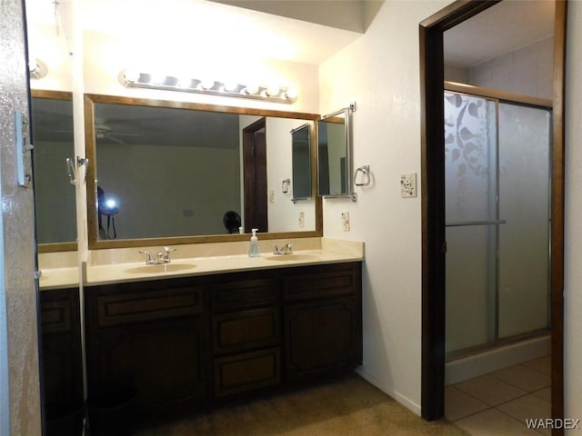 bathroom with double vanity, a sink, a shower stall, and tile patterned floors