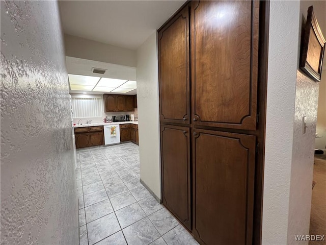 corridor with light tile patterned floors, visible vents, and a textured wall